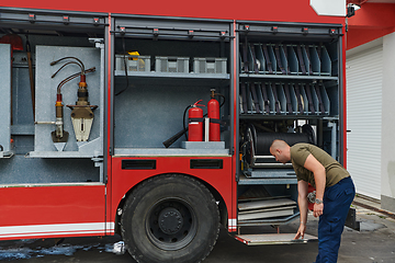 Image showing A dedicated firefighter preparing a modern firetruck for deployment to hazardous fire-stricken areas, demonstrating readiness and commitment to emergency response