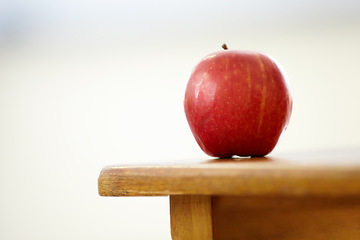 Image showing Red apple, desk and classroom for natural diet, snack or nutrition and fiber on table. Closeup of fresh organic fruit or food for eating, health and wellness on mockup space in empty class at school