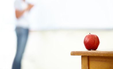 Image showing Red apple, teacher and desk in classroom for natural diet, snack or nutrition with fiber on table. Closeup of fresh organic fruit or food for eating, health and wellness on mockup space at school