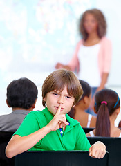 Image showing Portrait, student or child in classroom with hush, gossip or fingers on lips for quiet learning. Sign, study or boy learner with whisper or shush gesture for rumor, loud noise or silence in school