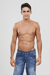 Image showing Man, portrait and bodybuilder in studio for fashion, pride and confident in jeans for style. Male person, shirtless and fitness or muscle progress, face and body care or wellness by gray background