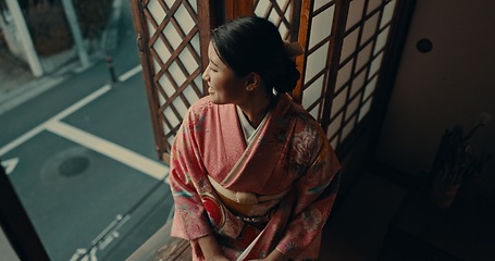 Image showing Japanese woman, window view and traditional clothes in home for vision, ideas or remember by street. Girl, person or thinking with smile, happy memory or mindfulness in morning at apartment in Tokyo