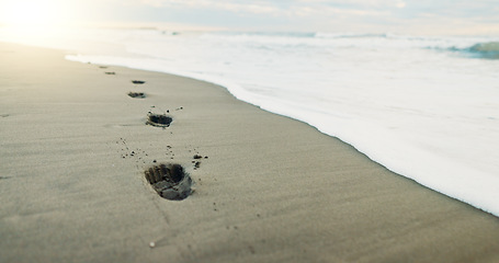 Image showing Footprints, sea and sand with beach and nature, environment and tropical landscape with travel. Adventure, journey and sunshine with closeup of ocean, waves with destination for vacation and outdoor