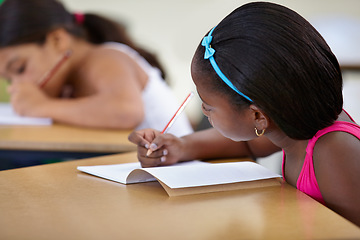 Image showing School, child and writing in book in classroom, desk and studying for education, knowledge or learning assessment. African girl, kid and student with notebook for academic development, test or lesson