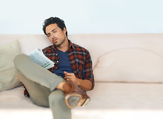 Image showing Man, reading and relax with newspaper on couch in home, living room and learning about event or story in media, News, mockup and person with article in the paper on sofa in apartment with information