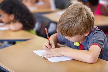 Image showing School, boy and kid writing in notebook in classroom, desk and studying for education, knowledge and academic assessment. Child, student and drawing in book for learning lesson, test and development