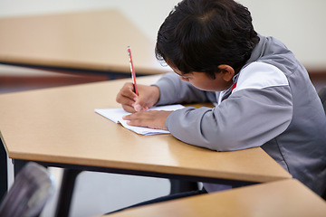 Image showing Boy, school and writing in classroom with notebook, studying lesson and learning knowledge at desk. Child, student and kid drawing on paper for academic development, educational test and assessment