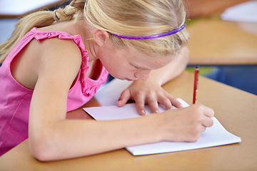 Image showing Girl, school and writing in classroom with notebook, studying lesson and learning assessment at desk. Child, student and kid drawing on paper for academic development, educational test and knowledge