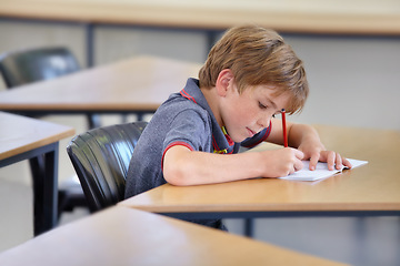 Image showing Boy, notebook and writing in school, classroom or studying academic assessment, learning lesson or test at table. Student, child and kid drawing notes on paper for education, development or knowledge