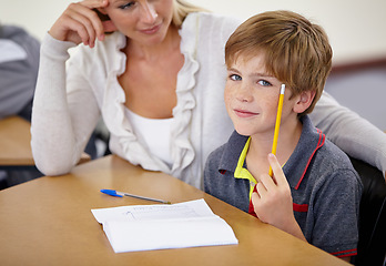 Image showing Teacher woman, classroom and boy at desk in portrait with support, advice and knowledge for education. People, learning and development for person, child and pencil for progress, school or academy