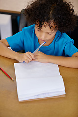 Image showing Student, thinking and child writing in notebook above desk with pencil, paper and learning in school. Kid, education and start of study on table in class with question or curiosity from lesson