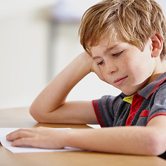 Image showing Class, notebook and bored boy at desk, learning and education with school exam. Reading book, studying for test and child student in classroom with knowledge and thinking with depression on project.