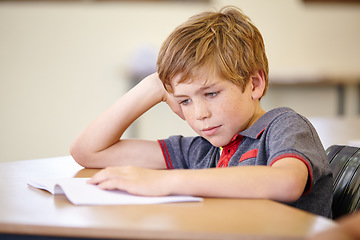 Image showing Class, book and bored child at desk, learning and education with school exam. Reading notebook, studying for test and boy student in classroom with knowledge and thinking with depression on project.