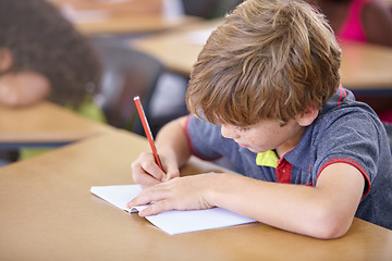 Image showing School, boy and writing in book in classroom, desk and studying for education, knowledge and learning assessment. Child, kid and student drawing in notebook for academic development, test and lesson