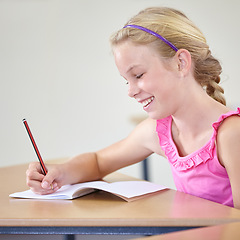 Image showing Kid, school and smile for writing in classroom, studying lesson or learning knowledge at desk. Child, student or happy girl drawing in notebook of academic development, educational test or assessment