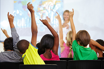 Image showing Back of children, teacher and raise hands for questions, education or learning with geography quiz in classroom. Youth, group of students and school for teaching support, map ideas and answer or yes