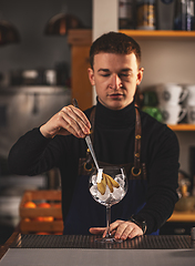 Image showing Professional bartender decorates cocktail