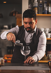 Image showing Barman putting ice cubes into glass