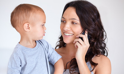 Image showing Mom holding toddler in home with phone call, smile and child care with support in morning. Happy woman, baby boy and bonding together in bedroom with chat on cellphone, multitasking and mothers love.