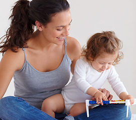 Image showing Mom playing with happy baby in home with toys, bonding and child care with support in morning on bed. Woman, playful toddler girl and fun together in bedroom with development, smile and abacus.