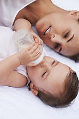 Image showing Above, care and a mother with a baby and milk for nutrition, health and growth development. Morning, family and a young mom and child with a bottle in the bedroom of a house for food and a drink