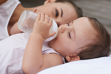 Image showing Calm, happy and a mother with a baby and milk for nutrition, health and growth development. Morning, family and a young mom and child with a bottle in the bedroom of a house for food and a drink