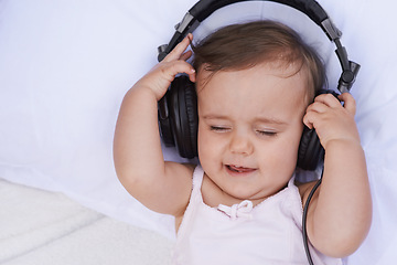 Image showing Baby, headphones and streaming music to relax, radio and listening to podcast on bed at home. Girl, kid and hearing sound for child development or learning, toddler and calming playlist for audio