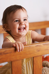 Image showing Excited baby in crib, playing with smile and fun in home, child development and care in home. Toddler girl in cot with playful face, energy and happiness in cute kids bedroom, nursery or apartment.