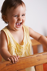 Image showing Cute, happy and a child in a crib for playing, wake up or comfort in a bedroom. Laughing, baby and a young kid in a nursery or room for thinking, idea or innocent standing for development in a home
