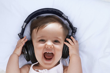 Image showing Baby, headphones and music in portrait and singing, streaming radio and podcast on bed at home. Girl, relax and hearing audio for child development or learning, toddler and fun playlist for kid