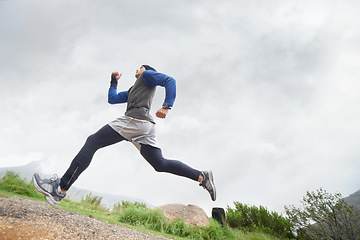 Image showing Low angle, runner and man running in nature training, cardio exercise and endurance workout for wellness. Sports, fitness or healthy male athlete on fast jog on mountain outdoors with speed or action