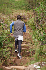 Image showing Steps, runner and man running in nature training, cardio exercise and endurance workout for wellness. Sports, fitness or back of healthy athlete on jog in a forest, uphill or mountain trail outdoors