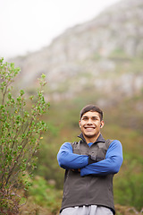 Image showing Smile, portrait and a man with arms crossed in nature for fitness, walking and exercise. Happy, morning and a male athlete or person on the mountains with pride for hiking, training or health