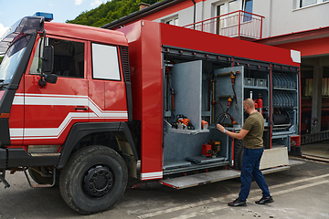 Image showing A dedicated firefighter preparing a modern firetruck for deployment to hazardous fire-stricken areas, demonstrating readiness and commitment to emergency response