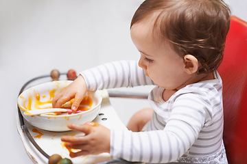 Image showing Eating, puree and girl baby in chair with vegetable food for child development at home. Cute, nutrition and hungry young kid or toddler enjoying healthy lunch, dinner or supper meal at house.