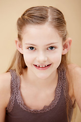 Image showing Child, portrait and smile in studio for youth confidence on brown background as mockup space, innocence or relax. Female person, model and face of young student for positive mood, cute or natural