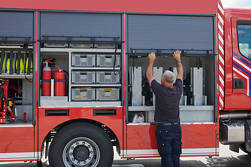 Image showing A dedicated firefighter preparing a modern firetruck for deployment to hazardous fire-stricken areas, demonstrating readiness and commitment to emergency response