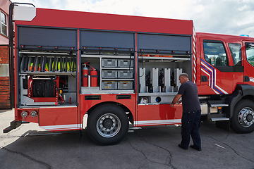 Image showing A dedicated firefighter preparing a modern firetruck for deployment to hazardous fire-stricken areas, demonstrating readiness and commitment to emergency response