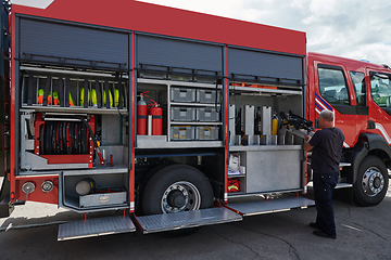 Image showing A dedicated firefighter preparing a modern firetruck for deployment to hazardous fire-stricken areas, demonstrating readiness and commitment to emergency response