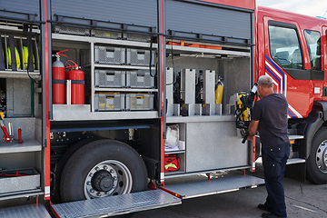 Image showing A dedicated firefighter preparing a modern firetruck for deployment to hazardous fire-stricken areas, demonstrating readiness and commitment to emergency response