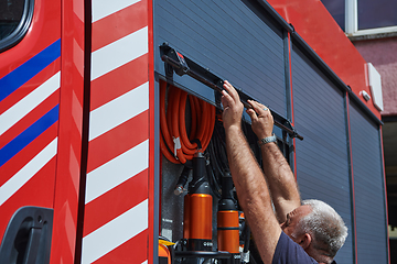 Image showing A dedicated firefighter preparing a modern firetruck for deployment to hazardous fire-stricken areas, demonstrating readiness and commitment to emergency response