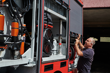 Image showing A dedicated firefighter preparing a modern firetruck for deployment to hazardous fire-stricken areas, demonstrating readiness and commitment to emergency response