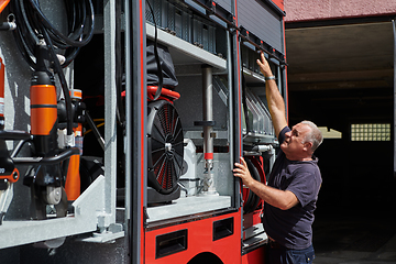 Image showing A dedicated firefighter preparing a modern firetruck for deployment to hazardous fire-stricken areas, demonstrating readiness and commitment to emergency response