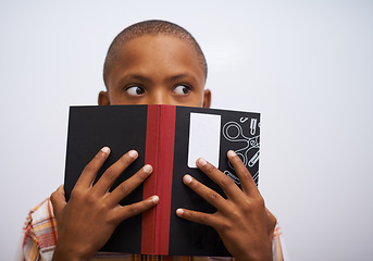 Image showing Student, classroom and hide face with book to read in front for classmates, shy and learning. Elementary school, boy and prepared oral with workbook, childhood development and academic education