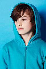 Image showing Studio, fashion or young kid in hoodie, trendy apparel or stylish outfit isolated on blue background. Cotton fabric, adolescent boy and youth child with clothes, casual outfit and looking at style