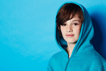 Image showing Studio portrait, fashion and child in hoodie, trendy apparel or stylish clothes isolated on blue background. Mockup space, fashionable style and face of boy with warm winter fabric and casual outfit