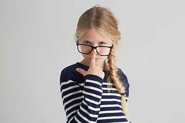 Image showing Child, portrait and glasses with serious in mockup, thought and eyewear or nose in studio. Girl, face or geek with blonde hair in fashion with vision, contemplation or smart kid by white background