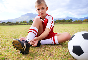 Image showing Boy, soccer player and ball with shoe laces, portrait and ready for game, shoes or child. Outdoor, exercise and sport for childhood, person and athlete for match, training and workout on pitch