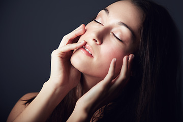 Image showing Woman, hands on face and natural beauty with skincare, cosmetics and wellness on dark background. Model touching skin, makeup and posing with eyes closed for dermatology shine or glow in studio