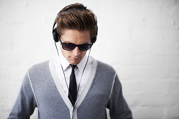 Image showing Man, headphones and listening to song and relaxing to music by wall background, sound and peace. Male person, meditation and streaming radio or podcast, playlist and hearing audio and wellness